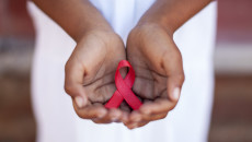 Child's hands holding an HIV awareness ribbon, Cape Town, South Africa